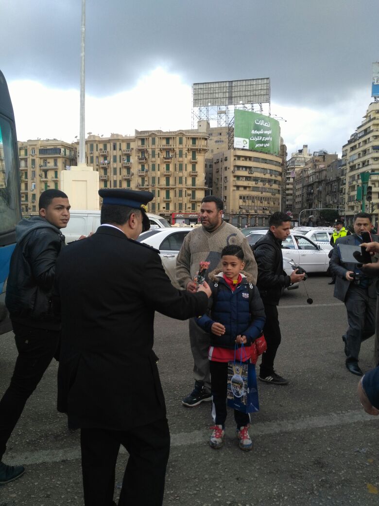 رجال الأمن يوزعون الورود بشوارع القاهرة