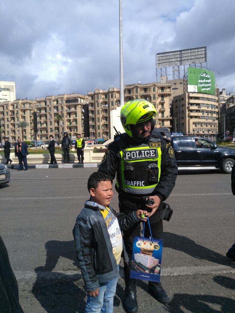رجال الأمن يوزعون الورود بشوارع القاهرة