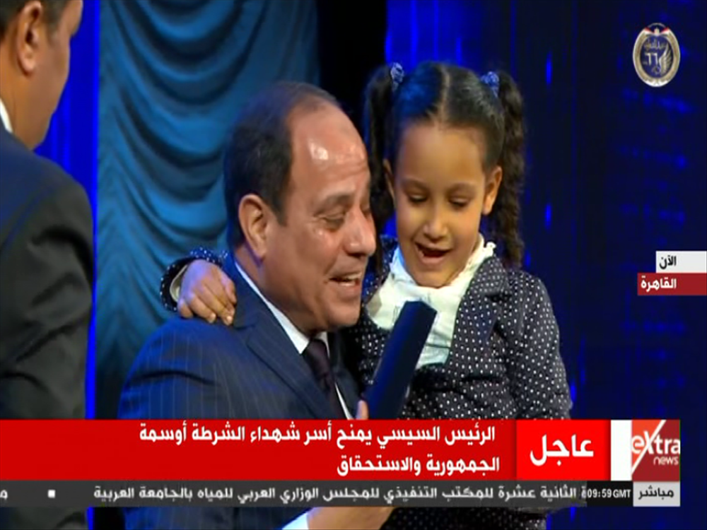 الرئيس السيسى يحمل طفلة شهيد خلال تسليمها وسام والدها بعيد الشرطة