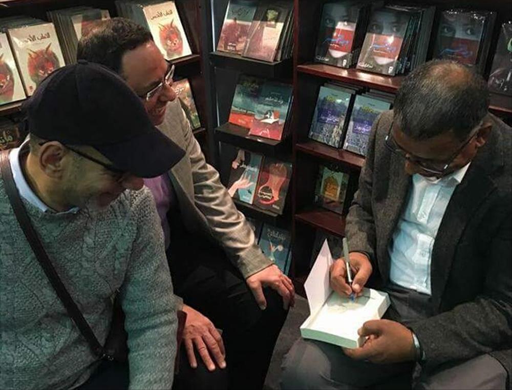 الصحفي محمد صلاح الزهار يوقع لأحد معجبيه على نسخة من الكتاب