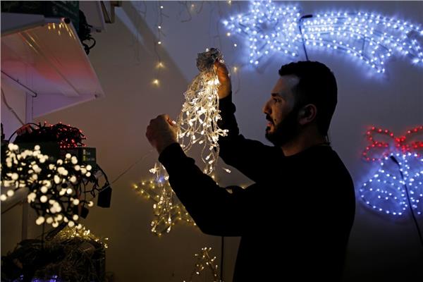 فلسطيني يرتب أضواء زينة في متجر استعدادا لموسم عيد الميلاد وسط تفشي فيروس كورونا 