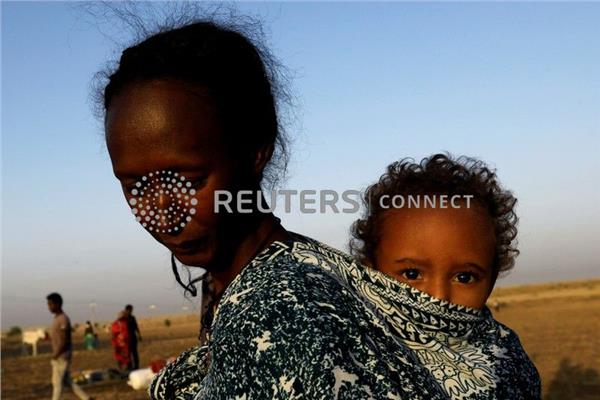 لاجئة اثيوبية تحمل طفلها قرب الحدود مع السودان (رويترز)