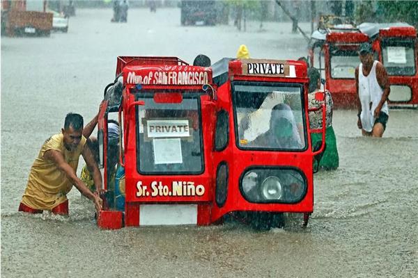 أشخاص يجرون عربة في شارع غرق جرّاء الأمطار الغزيرة في مينداناو في الفليبين