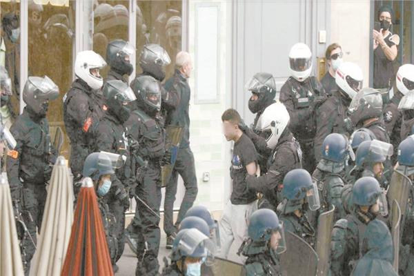 شرطيون يسيرون مع محتج موقوف خلال تظاهرة احتجاجا على إلزامية الشهادة الصحية فى باريس    