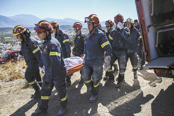رجال الإطفاء يحملون جثة قتيل بعد زلزال كريت «صورة من أ . ف . ب»