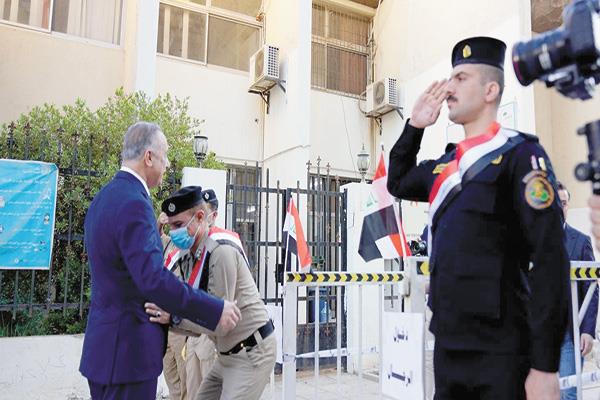 فرد أمن عراقى يقوم بواجبه بتفتيش الكاظمى قبل دخوله للتصويت بالمركز الانتخابى