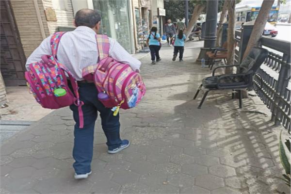 صورة الأب الذي يحمل حقيبتي مدرسة طفلتيه المنتشرة على منصات السوشيال ميديا