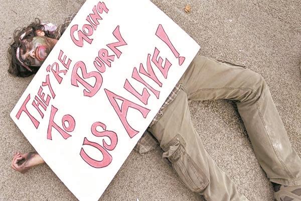 متظاهر مستلقٍ على الأرض مع لافتة «سيحرقوننا ونحن أحياء»     