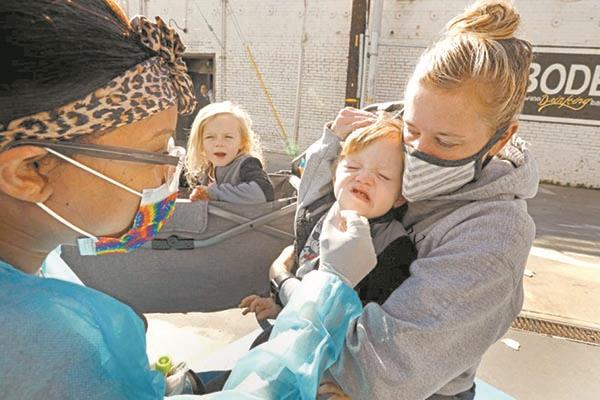 أمريكية تحمل طفلها خلال إجرائه اختبار فحص الفيروس فى كاليفورنيا      