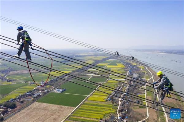 عمال صينيون يمشون على أسلاك كهرباء ارتفاعها 280 مترا 