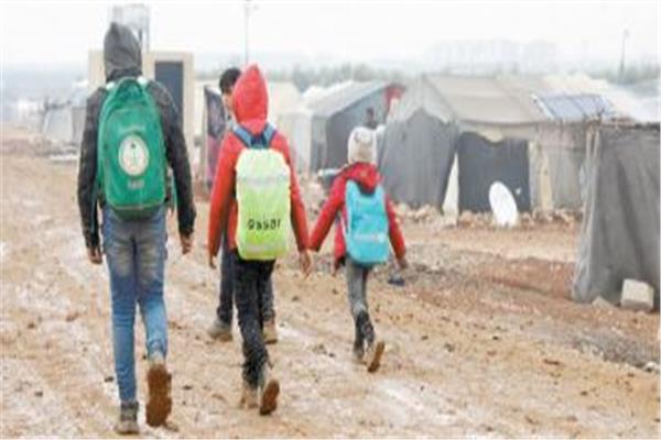 أطفال سوريون نازحون يسيرون فى الوحل بمخيم فى مدينة أعزاز شمالى سوريا