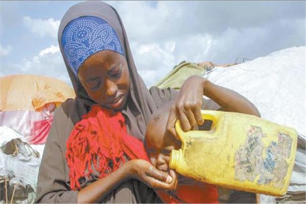 امرأة صومالية فرت من المناطق المنكوبة بالجفاف تقدم الماء لطفلها فى مخيم للنازحين فى ضواحى مقديشو