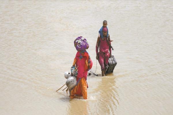 أسرة مع متاعها تجتاز مياه الأمطار والفيضانات فى باكستان «صورة من ا ف ب»