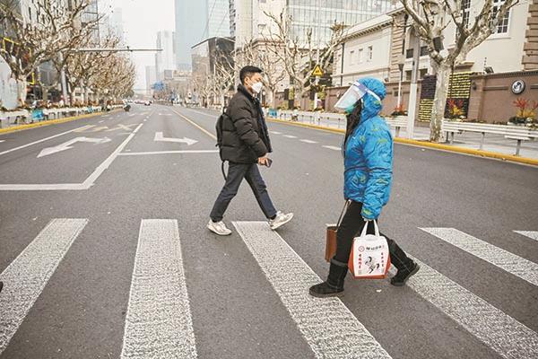 امرأة تمشي فى شوارع شنجهاي وترتدي درعًا للوجه وقناعًا خوفا من كورونا       
