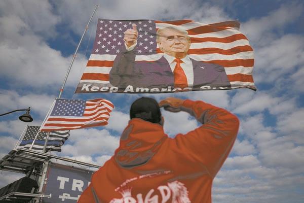 رجل يؤدى التحية العسكرية أمام علم يحمل صورة لترامب « صورة من أ ف ب »