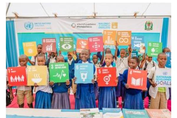 أطفال في تنزانيا يحملون لوحات ترمز لأهداف التنمية المستدامة السبعة عشر