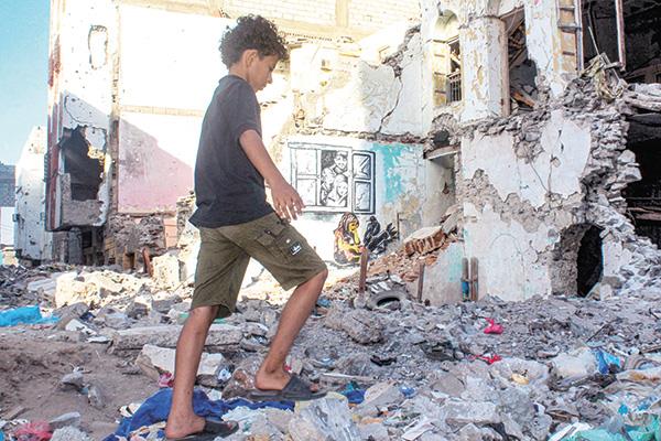 طفل يسير بالقرب من جدار مهدم نتيجة قصف
