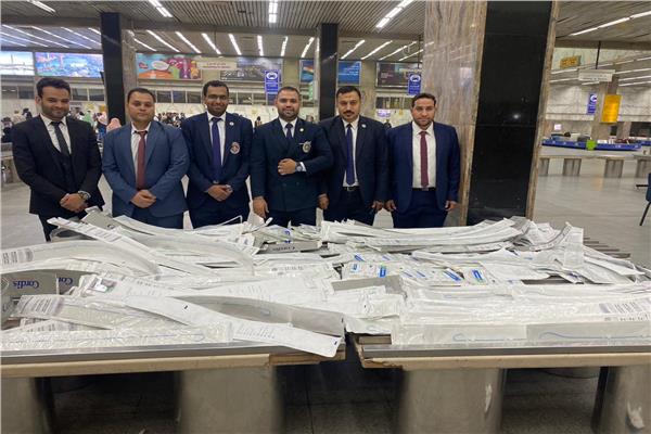 رجال الجمارك بمطار القاهرة وامامهم المضبوطات