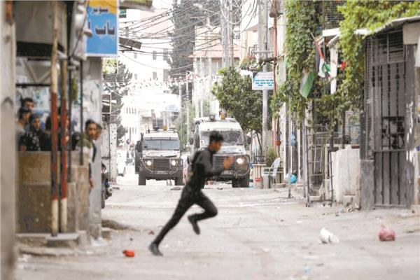 فلسطينى يبحث عن ساتر خلال اشتباكات مع قوات الاحتلال بنابلس