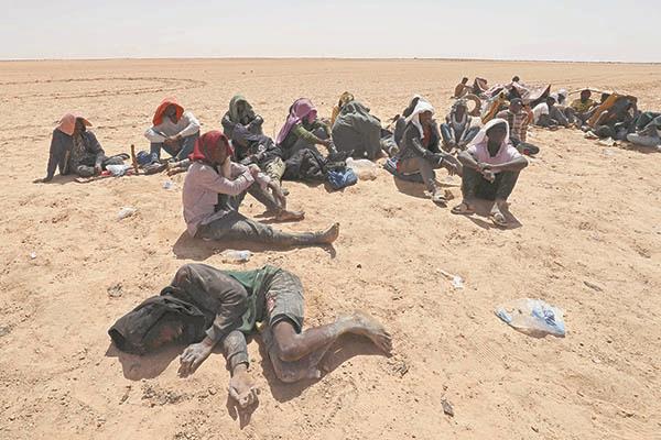 المهاجرون الذين أنقذتهم السلطات الليبية فى منطقة صحراوية قرب الحدود مع تونس   
