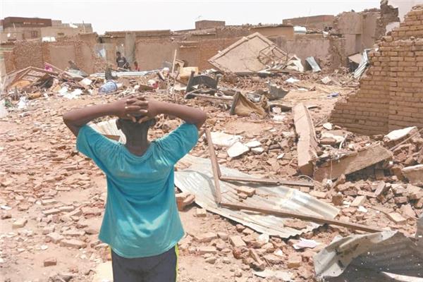 طفل سوداني ينظر بحسرة إلي ركام المباني المتضررة بسبب القتال في الخرطوم       