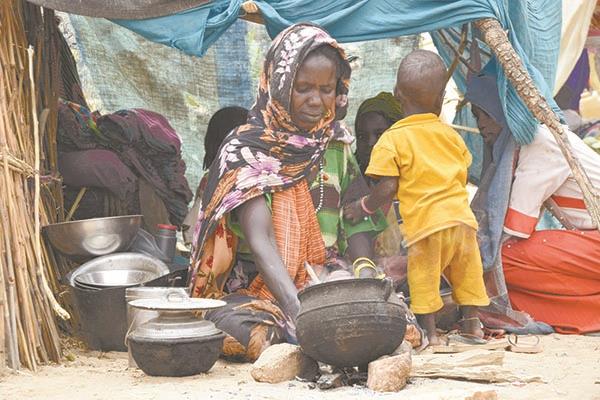 نازحة سودانية تعد الطعام فى مخيم بتشاد