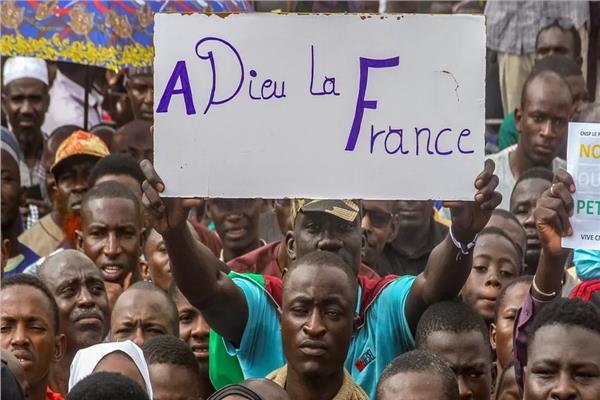 أحد المتظاهرين يرفع لافتة كتب عليها بالفرنسية "وداعا فرنسا"