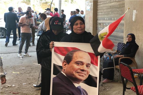 إحدى السيدات تحمل صورة الرئيس السيسي أمام الشهر العقاري