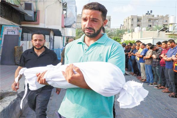 فلسطينى يحمل جثة طفل اسُتشهد فى القصف الإسرائيلى على غزة