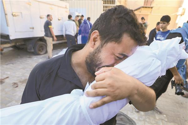 فلسطيني يبكي وهو يحمل جثمان قريب له وسط قطاع غزة