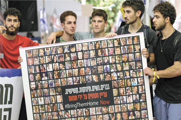 إسرائيليون يحملون صورة مجمعة للأسرى لدى حماس (أ ف ب)