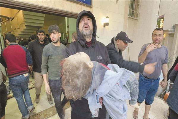 فلسطينى يحمل طفلاً مصابًا فى قصف إسرائيلى