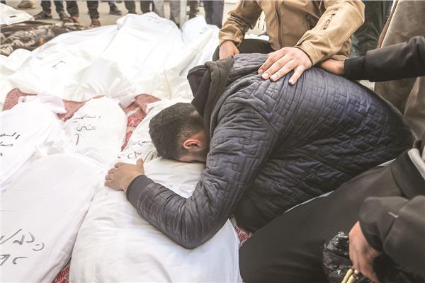 أحد الفلسطينيين يودع عائلته بعد سقوطهم شهداء جراء القصف الإسرائيلي       