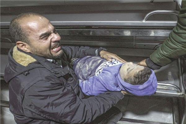 أب فلسطيني يبكي وهو يحمل جثمان ابنه جراء قصف إسرائيلي