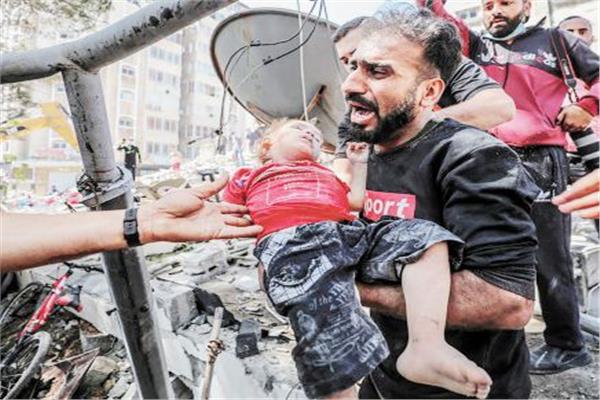 فلسطينى يحمل جثمان طفله بعدما انتشله من تحت الأنقاض