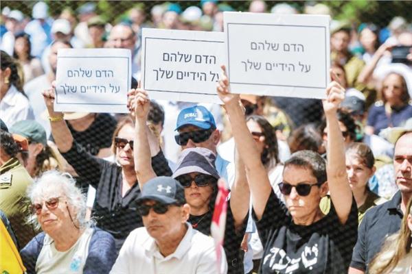 متظاهرون يرفعون لافتات احتجاجية ضد وزير الدفاع الإسرائيلي خلال يوم الذكرى