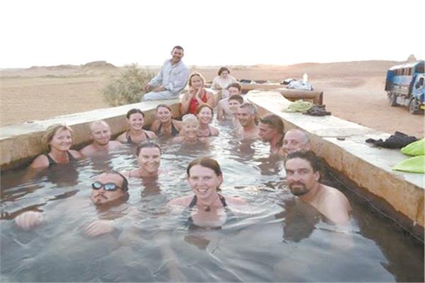 استمتاع الوفود السياحية داخل مياه الآبار الجوفية الكبريتية بالصحراء الغربية