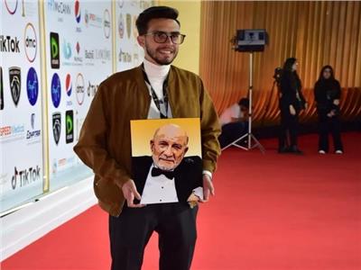 صور| حفيد أحمد خليل يحمل صورة جده على السجادة الحمراء لفيلم «رجل بلا وطن»