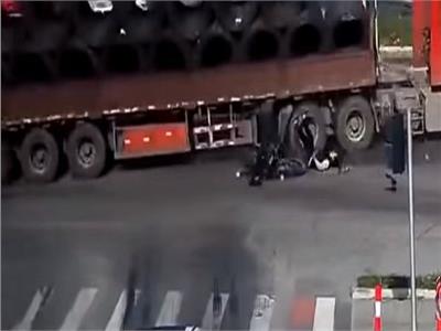نجاة سائق دراجة بخارية من الدهس تحت عجلات شاحنة ضخمة