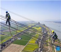 بالصور| صينيون يمشون على أسلاك كهرباء ارتفاعها 280 مترا فوق نهر اليانجتسي