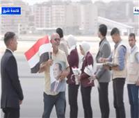 مواطن عائد من السودان يرفع صورة الرئيس السيسي وعلم مصر