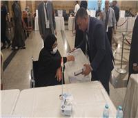 مندوب القنصلية المصرية بالسعودية يحمل صندوق لمسنة على كرسي متحرك لتضع صوتها 