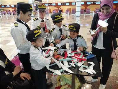 «الطيارون الصغار».. أطفال يصنعون طائرات ورق بمطار الغردقة