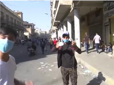 متظاهر عراقي يمسك فوارغ القنابل المسيلة  