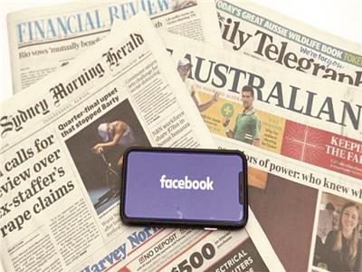شعار فيس بوك على شاشة موبايل خلف مجموعة من الصحف الاسترالية 