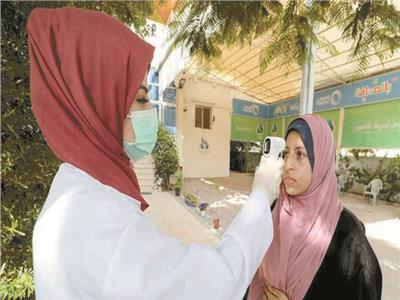 عاملة بالصحة تقيس درجة حرارة مواطنة فلسطينية 