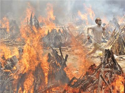  رجل يهرب من منطقة حرق جثامين ضحايا كورونا بالهند «صورة من أ . ب»