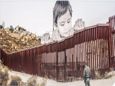  صورة طفل مكسيكى يحدق من الجانب المكسيكى عبر الحدود مع أمريكا