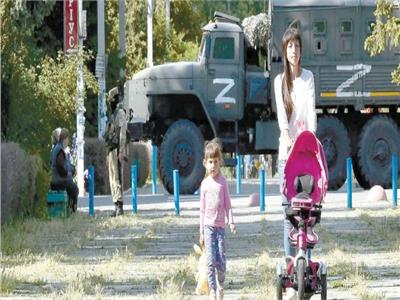 سيدة أوكرانية تترجل مع طفليها بشوارع مدينة خيرسون بالقرب من دورية عسكرية روسية    