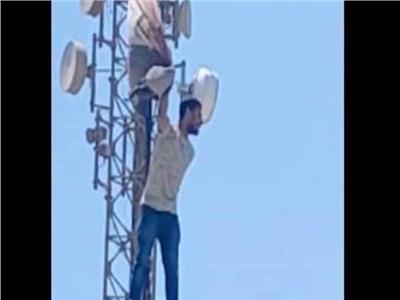بالصور..شاب يهدد بالقفز من أعلي برج ارسال هوائي بالمنيا يطالب بعودته للعمل 
